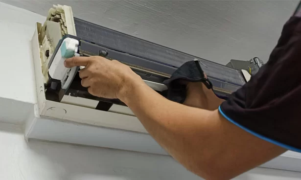 Technician performing cleaning of air conditioning indoor evaporator coil